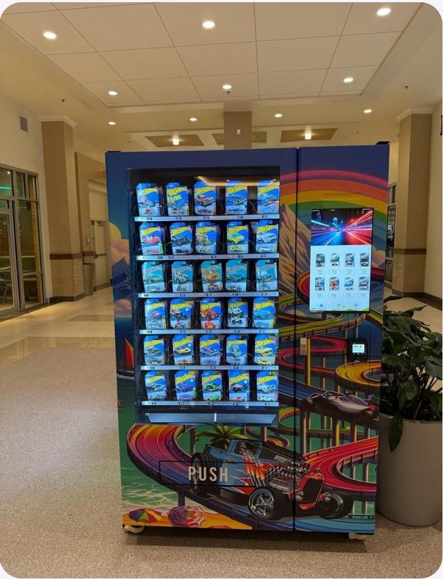 J&J die-cast machine with a full-body wrap on a shopping center floor